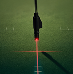 Laser alignment trainer mounted on a putter during indoor practice